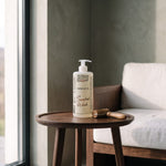 Sandal Wood Massage Oil 500 ml with a wooden massage roller on a side table