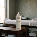 Magnesium Massage Oil 500 ml on a low wooden table in a spa treatment room